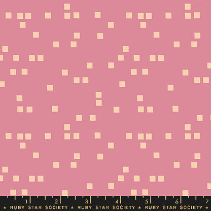 A pink fabric or material swatch with a repeating pattern of small pale cream squares, plus a black ruler strip along the bottom edge labeled Ruby Star Society.