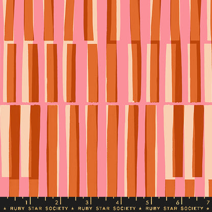 Fabric with a repeating geometric pattern of vertical rectangular bars in orange, rust, peach, and cream on a pink background, with a black ruler strip labeled RUBY STAR SOCIETY along the bottom edge.