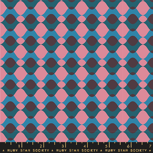 Fabric with a repeating geometric pattern of pink and dark purple teardrop shapes over a teal blue background, with a Ruby Star Society ruler along the bottom edge showing scale.