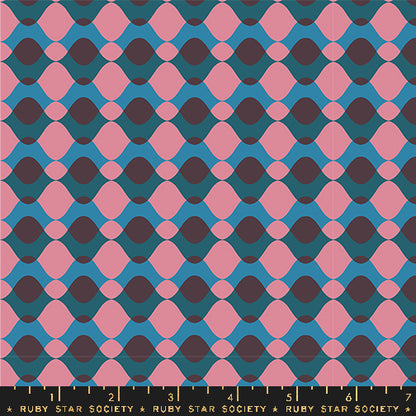 Fabric with a repeating geometric pattern of pink and dark purple teardrop shapes over a teal blue background, with a Ruby Star Society ruler along the bottom edge showing scale.