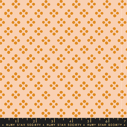 A repeating fabric pattern featuring small orange-brown floral clusters on a warm peach background, with a black Ruby Star Society ruler along the bottom edge.