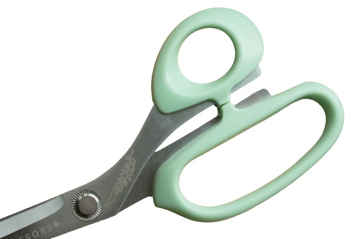 Pair of scissors with green handles on a white background for sewing and crafting.