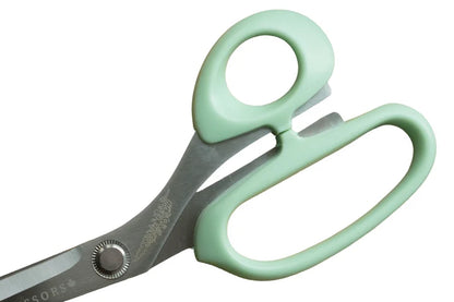 Pair of scissors with green handles on a white background for sewing and crafting.