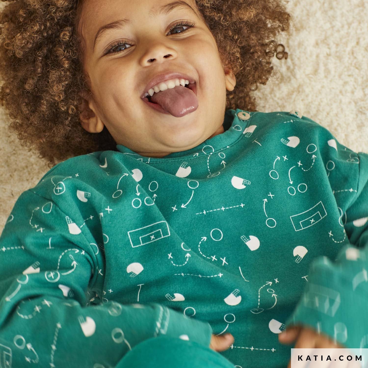 Picture of a child wearing a green sweatshirt with a rugby theme