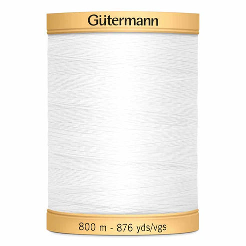 Spool of white cotton quilting thread with gold cap and label on a white background
