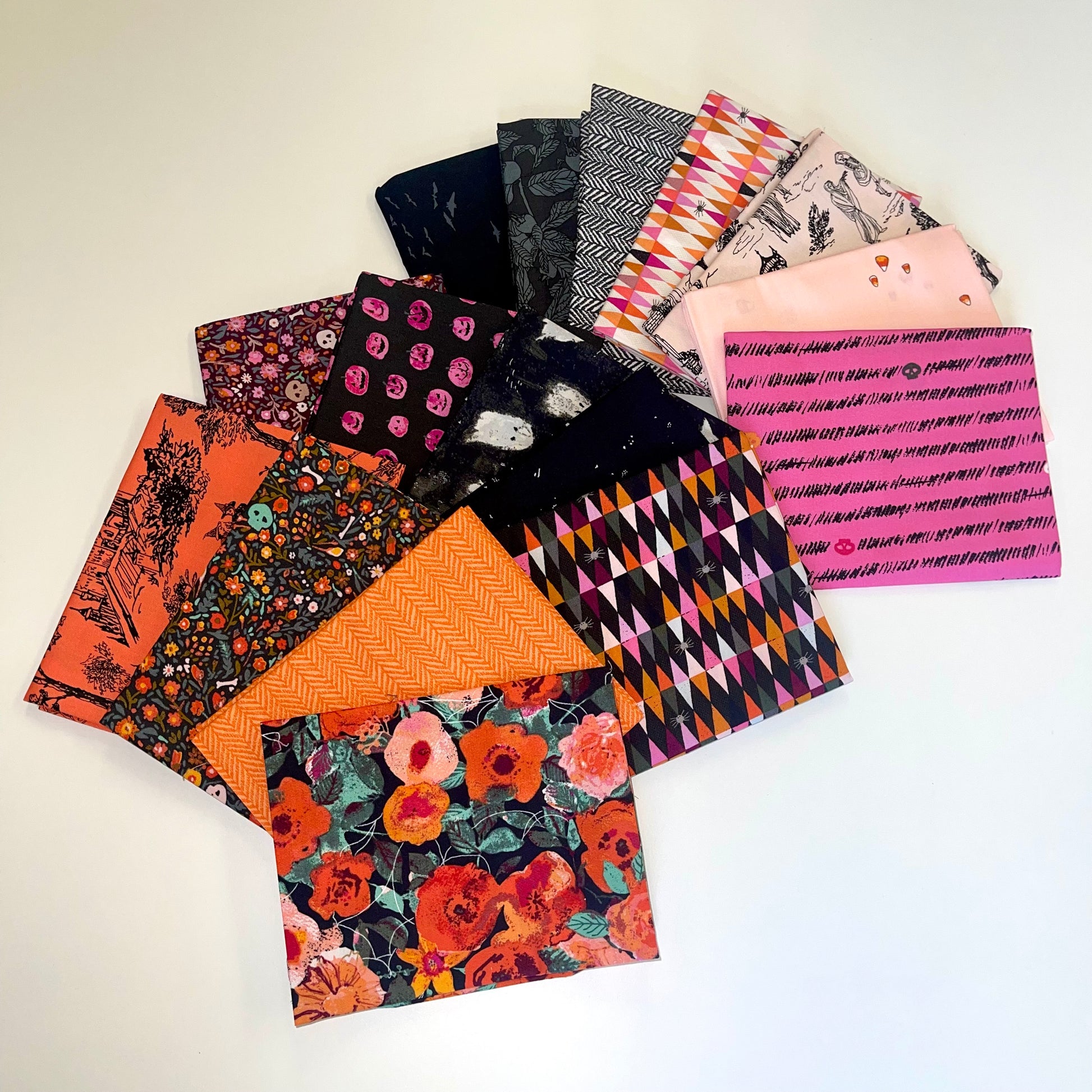 Collection of halloween fat quarters patterned fabric squares on a light background for sewing quilting and crafting