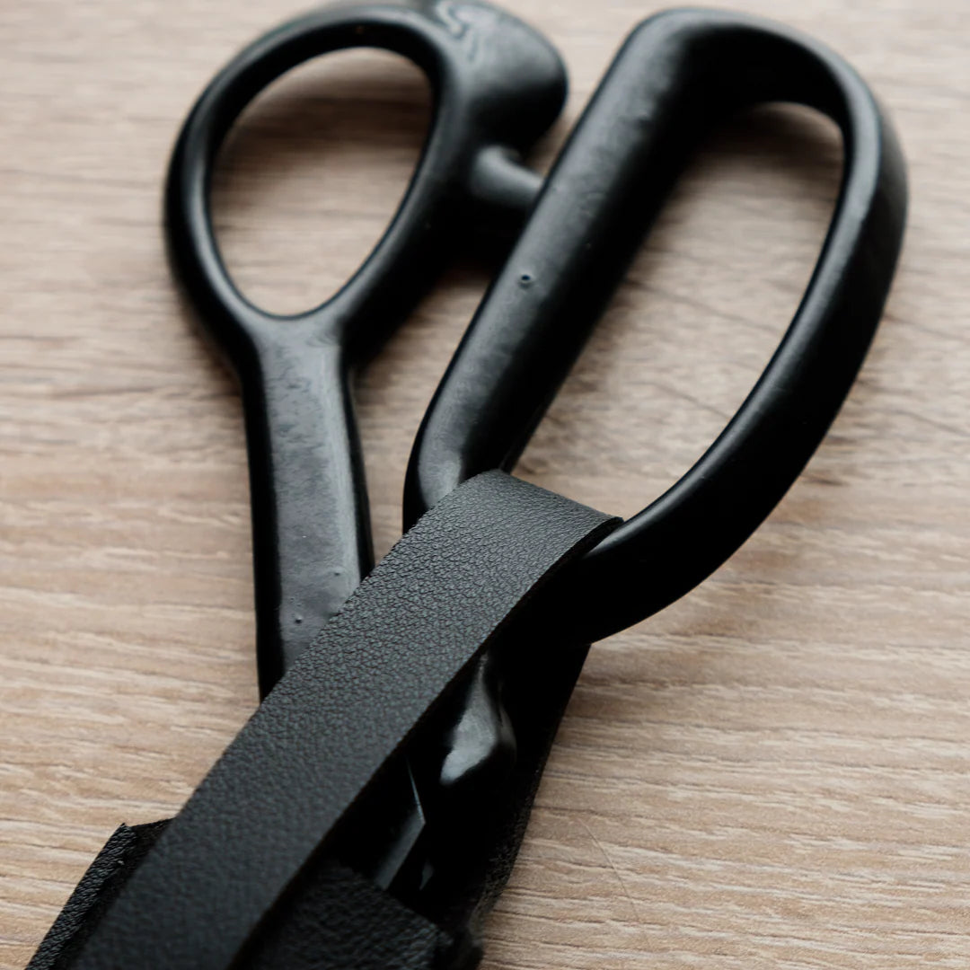Handle and secure fastening on a black leather scissor or shear sheath.