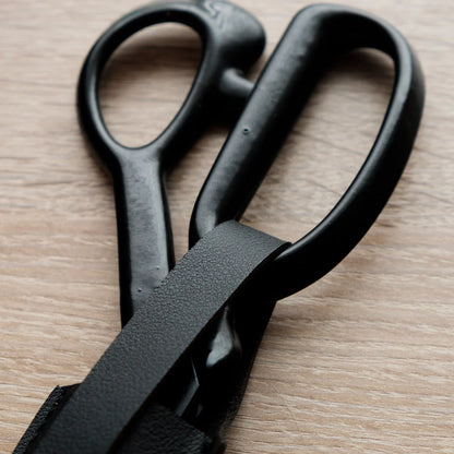 Handle and secure fastening on a black leather scissor or shear sheath.