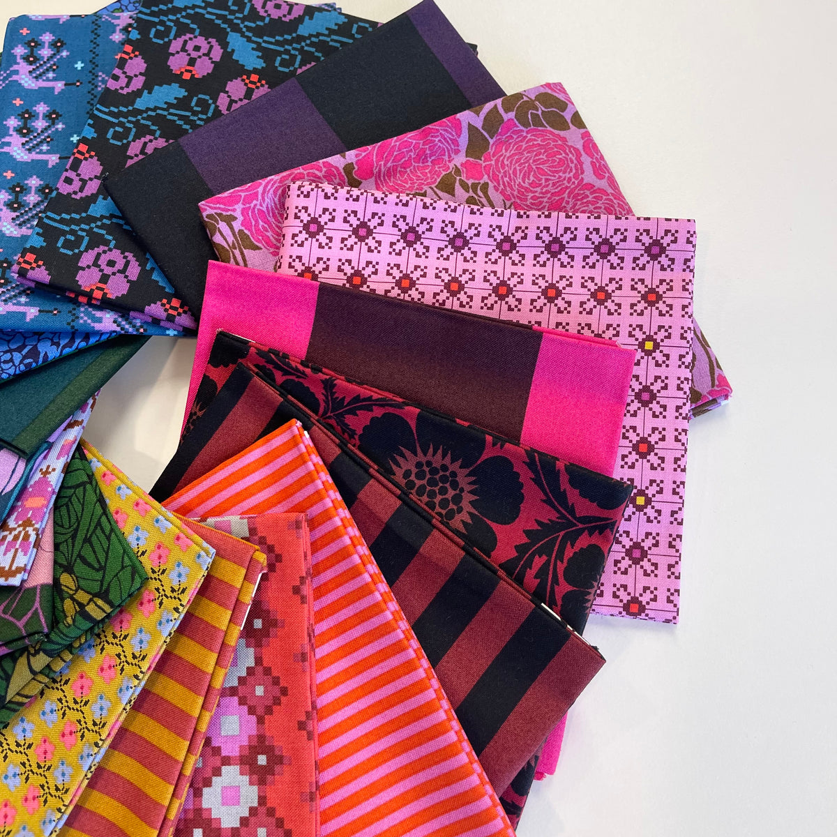 A pile of bold and vibrant fat quarter fabric pieces from Anna Maria Textiles for sewing and quilting. 