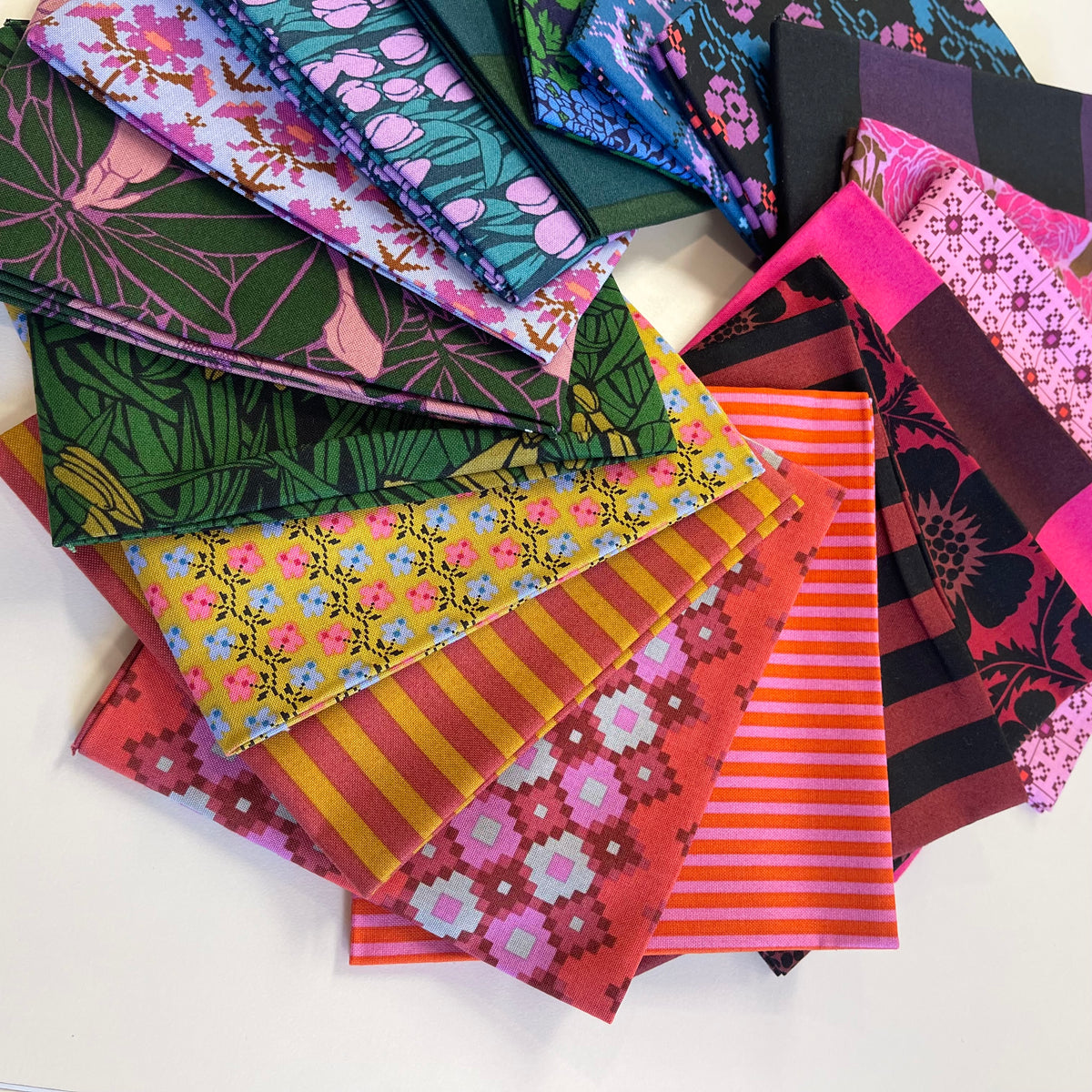 A pile of bold and vibrant fat quarter fabric pieces from Anna Maria Textiles for sewing and quilting. 