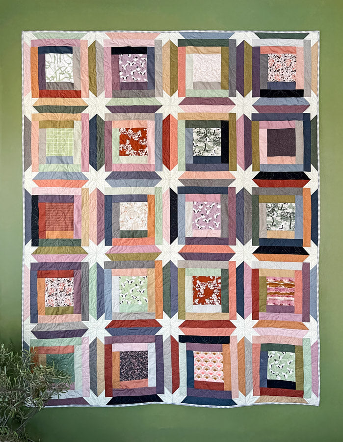 Quilt with square pattern on a green wall from Soar by Katerina Roccella Art Gallery Fabrics premium cotton for sewing and crafting.