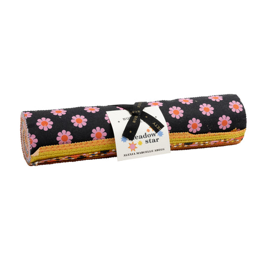 A rolled bundle of fabric pieces tied with a black ribbon and white paper label, featuring a black background with pink and orange daisy flowers on top and multicolored layers visible along the side - Meadow Star Ruby Star Society