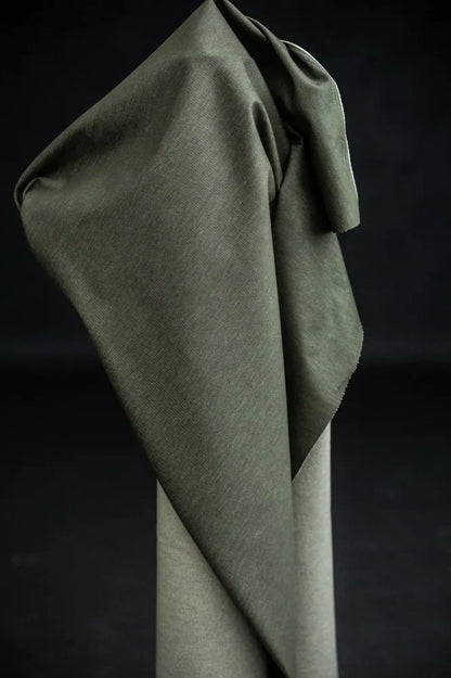 Green denim fabric organic cotton draped over a stand against a dark background
