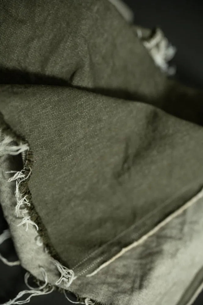 Close-up of a folded jean denim fabric with frayed edges in black and white.