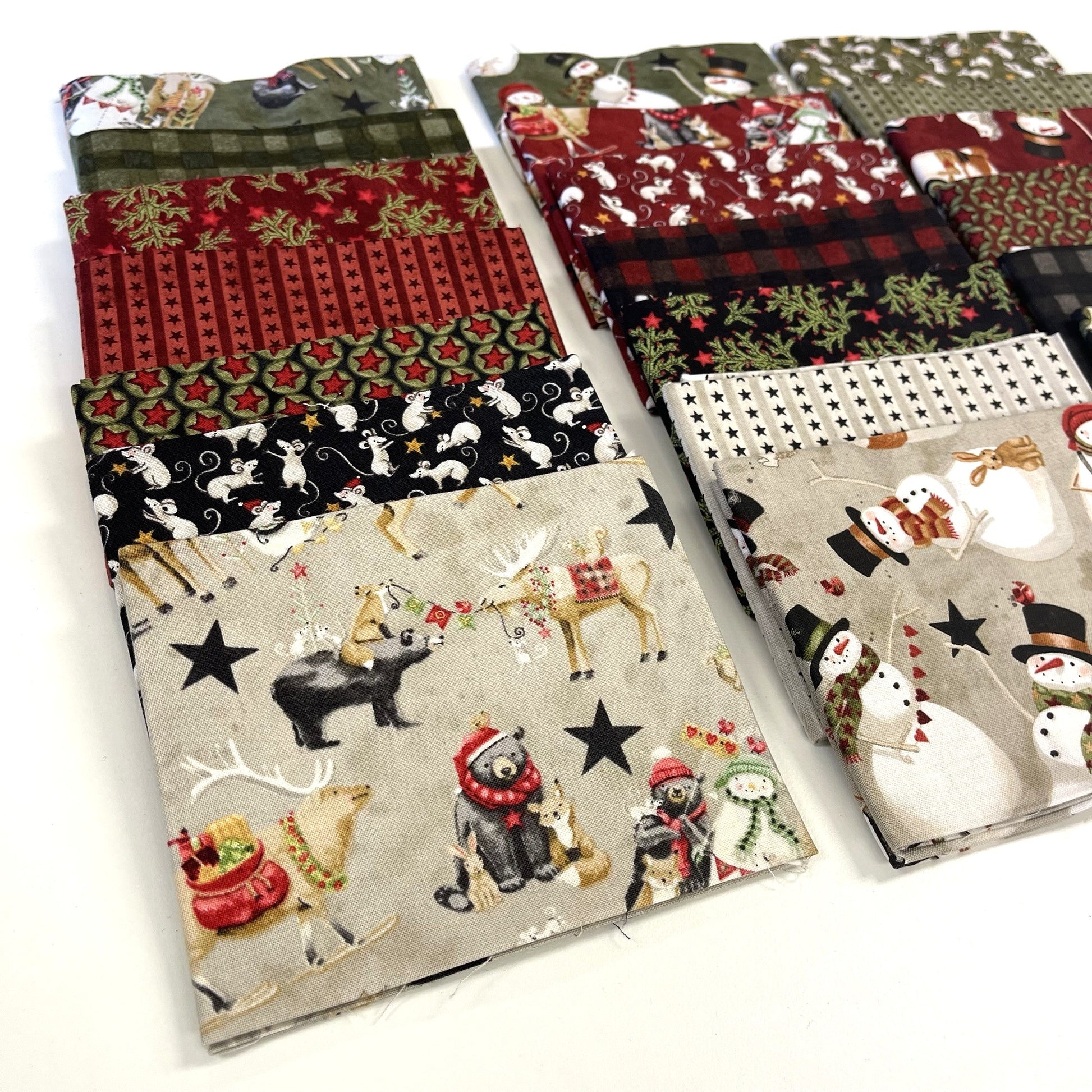 Collection of Christmas-themed fabric swatches with reindeer, snowmen, and other winter elements for sewing and quilting