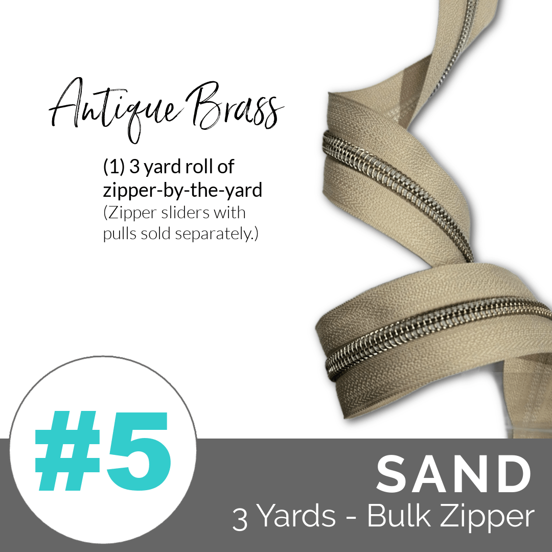 Sand-colored zipper roll with antique brass pull on a white background