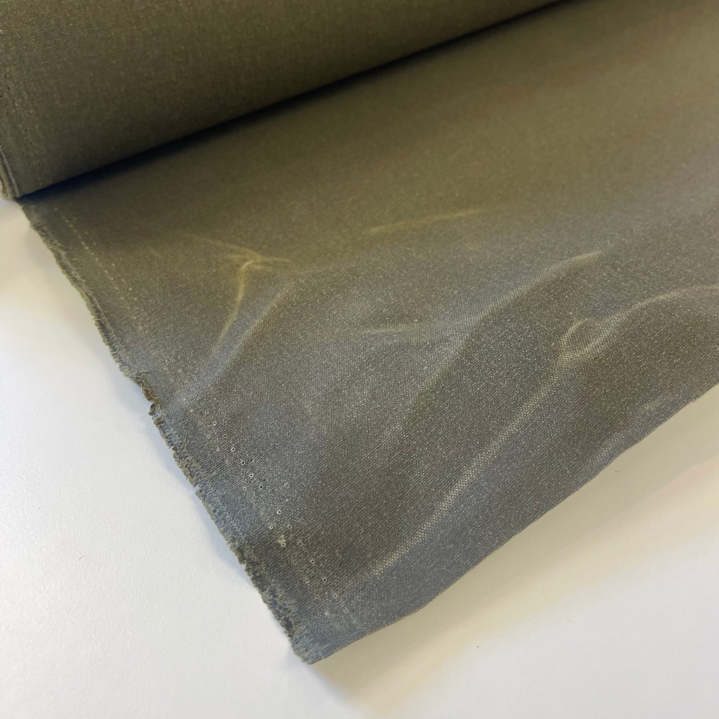 A close-up of a olive green waxed canvas fabric material for sewing and crafting and bag making.