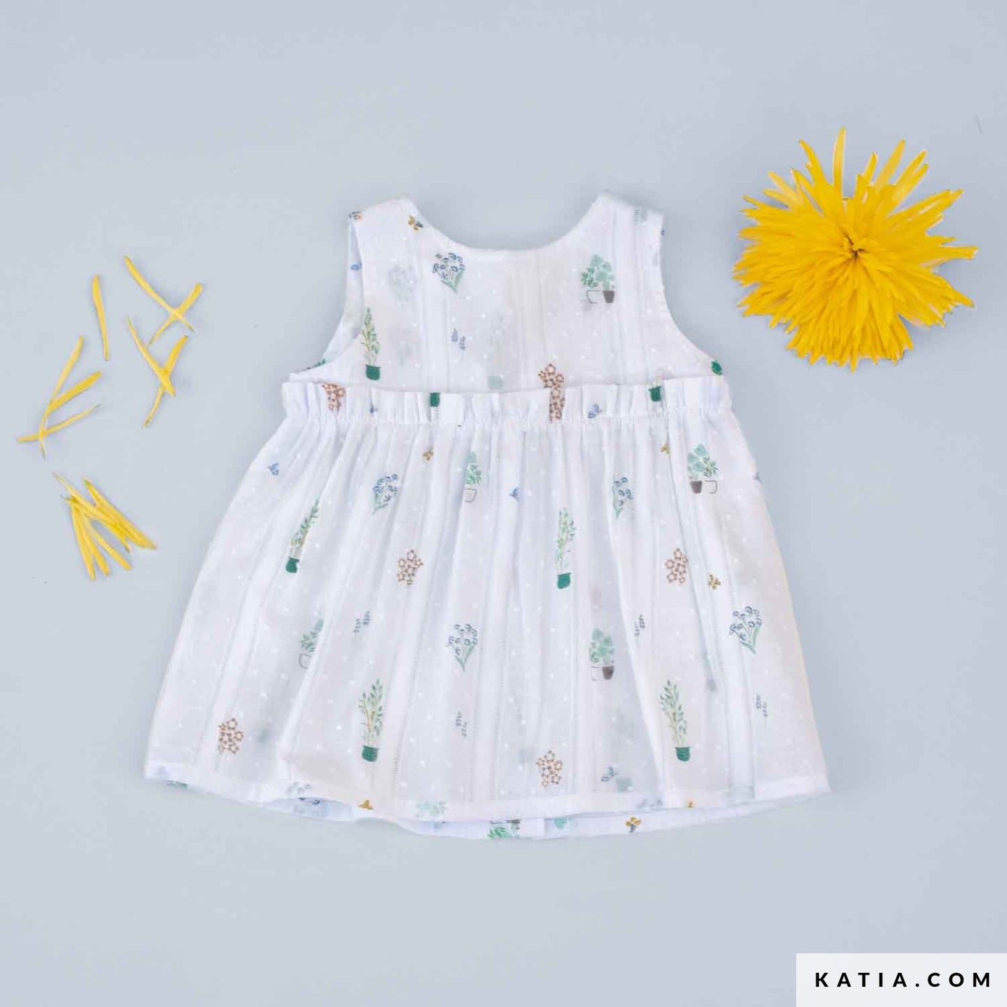 White baby dress in cotton fabric with small plant and flower illustrations. 