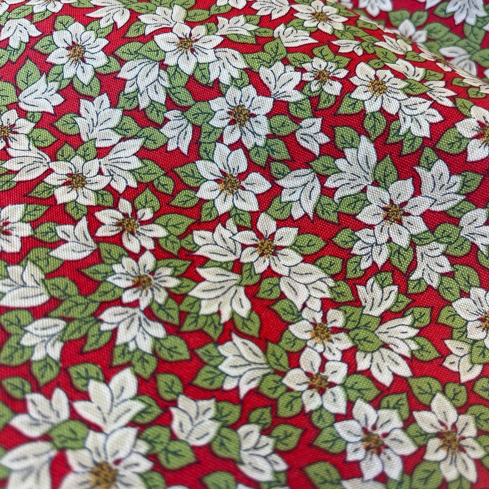 Fabric with white poinsettias on a red background from Liberty Fabrics for Christmas sewing, quilting, and crafting. 