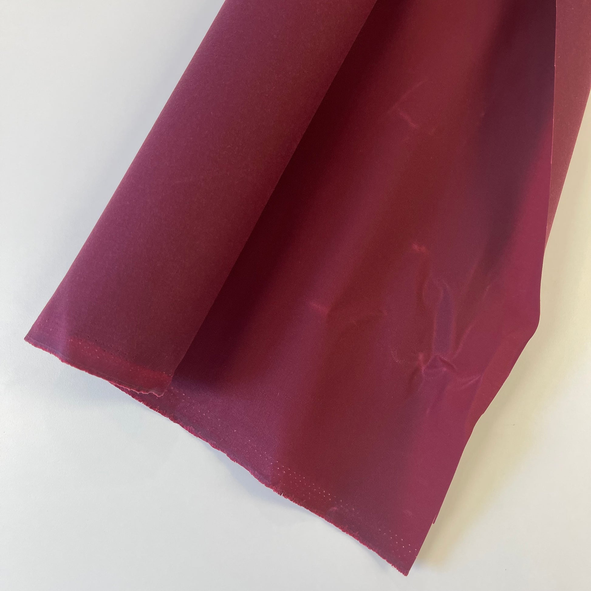 A close-up of dark red waxed canvas fabric material for sewing and crafting and bag making.