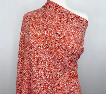 One-shoulder top with red floral pattern fabric on a mannequin against a gray background