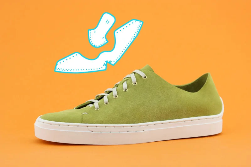 Green sneaker with white sole on an orange background