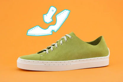 Green sneaker with white sole on an orange background