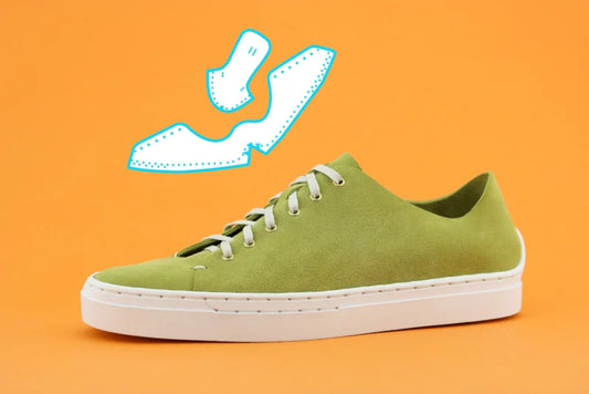 Green sneaker with white sole on an orange background