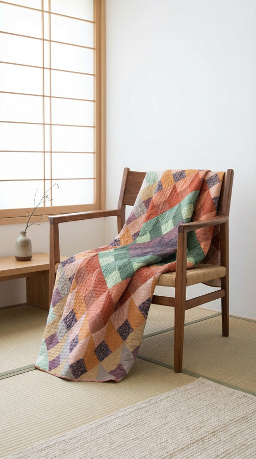 Colorful fabric quilt draped over a wooden chair in a room with a sliding door. from Soar by Katerina Roccella Art Gallery Fabrics premium cotton for sewing and crafting.
