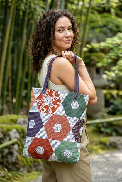 Woman holding a colorful geometric-patterned tote bag outdoors from Soar by Katerina Roccella Art Gallery Fabrics premium cotton for sewing and crafting.