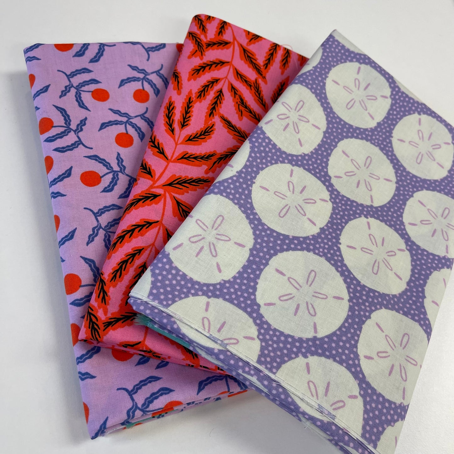 Three ruby star society fabric swatches with different patterns on a white background