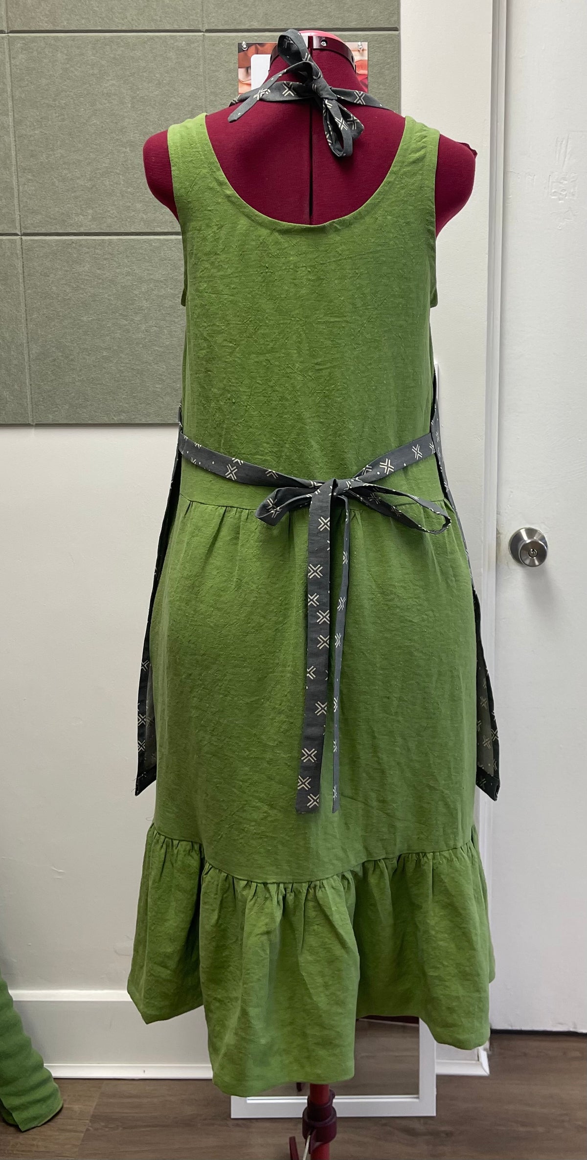 a tie back apron in cotton linen blend displayed on a sewing dummy for sewing lesson and workshop.