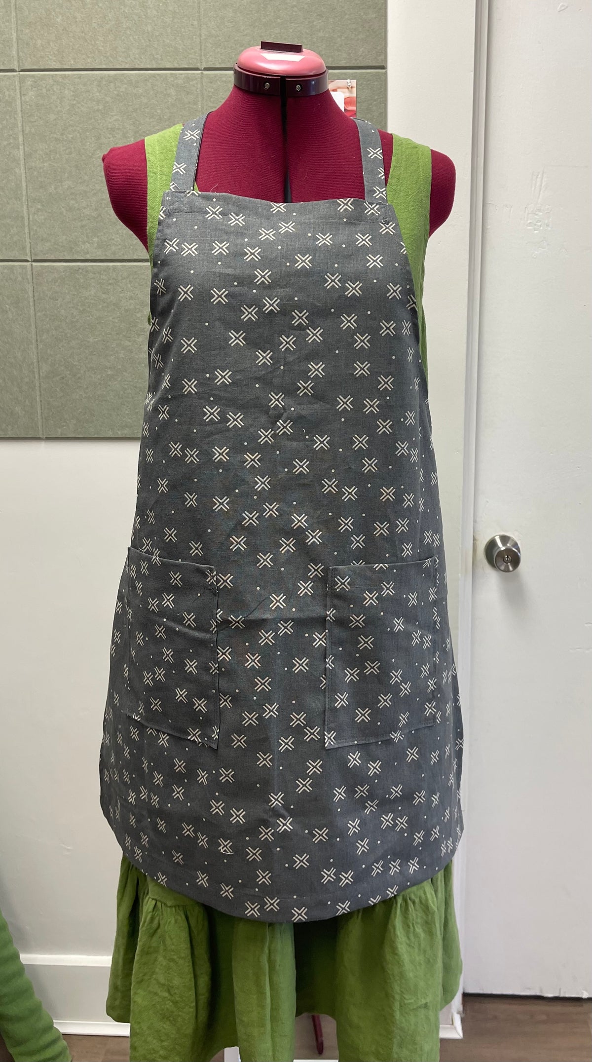a tie back apron in cotton linen blend displayed on a sewing dummy for sewing lesson and workshop.