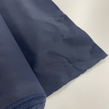 A close-up of a navy waxed canvas fabric material for sewing and crafting and bag making.