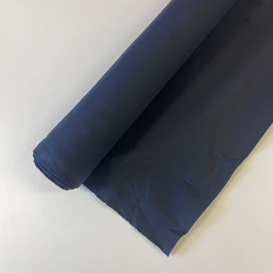 A close-up of a navy waxed canvas fabric material for sewing and crafting and bag making.