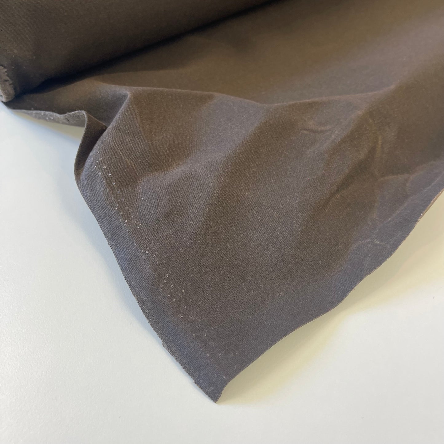 A close-up of dark brown waxed canvas fabric material for sewing and crafting and bag making.