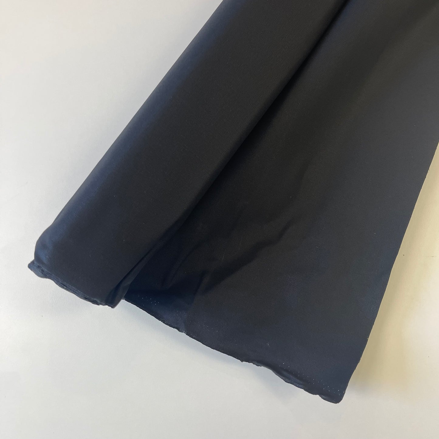A close-up of a black wax canvas material for sewing and crafting. 