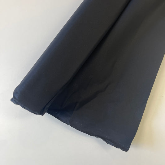 A close-up of a black wax canvas material for sewing and crafting. 