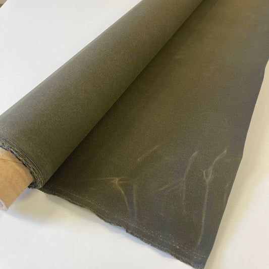 A close-up of a olive green waxed canvas fabric material for sewing and crafting and bag making.