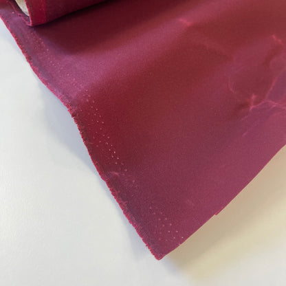 A close-up of dark red waxed canvas fabric material for sewing and crafting and bag making.