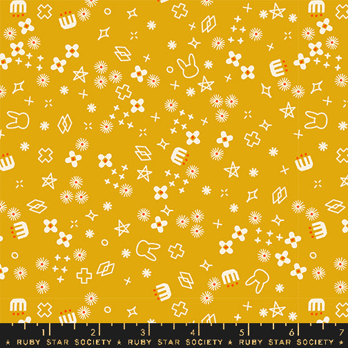 Patterned fabric with white shapes on a yellow background, featuring stars, flowers, and abstract designs.