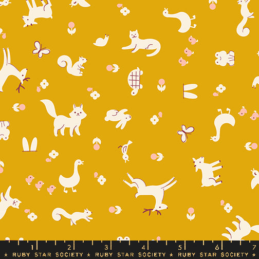 Pattern of white animals and birds on a mustard yellow background with a ruler at the bottom.