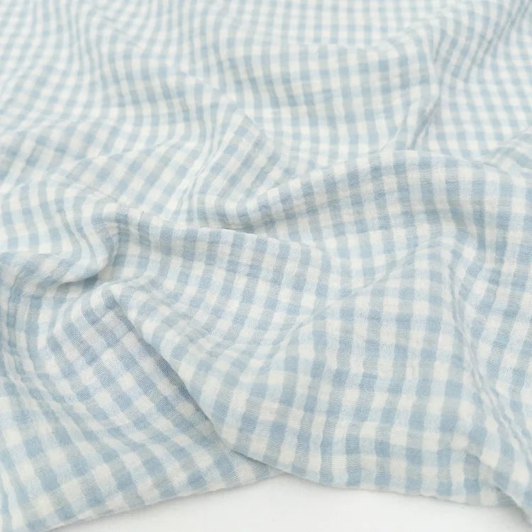 Blue and white checkered organic cotton double gauze fabric on a white background
