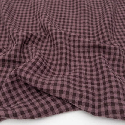 Close-up of purple checkered 100% cotton organic fabric on a white background