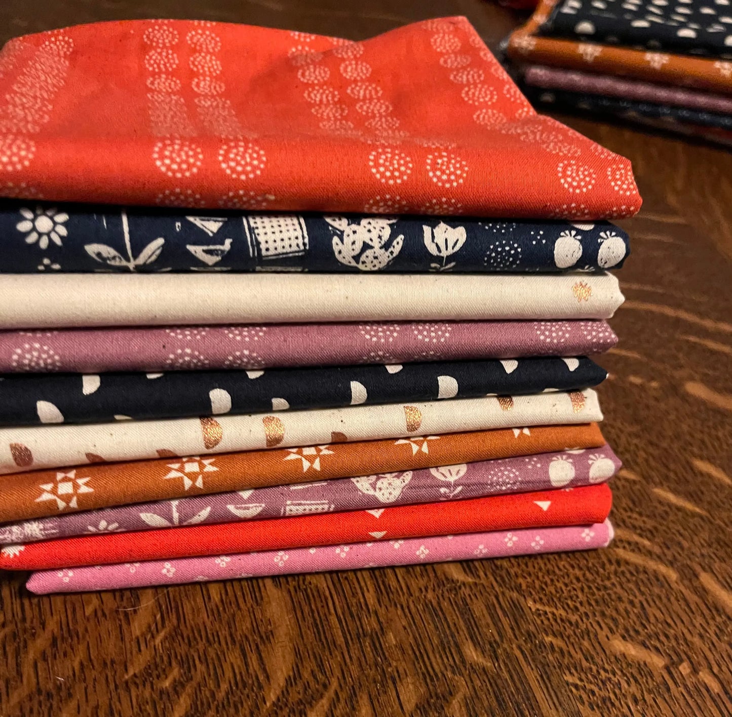 pile of fat quarter fabric cuts in reds blues purples and whites. from heirloom by ruby star  society